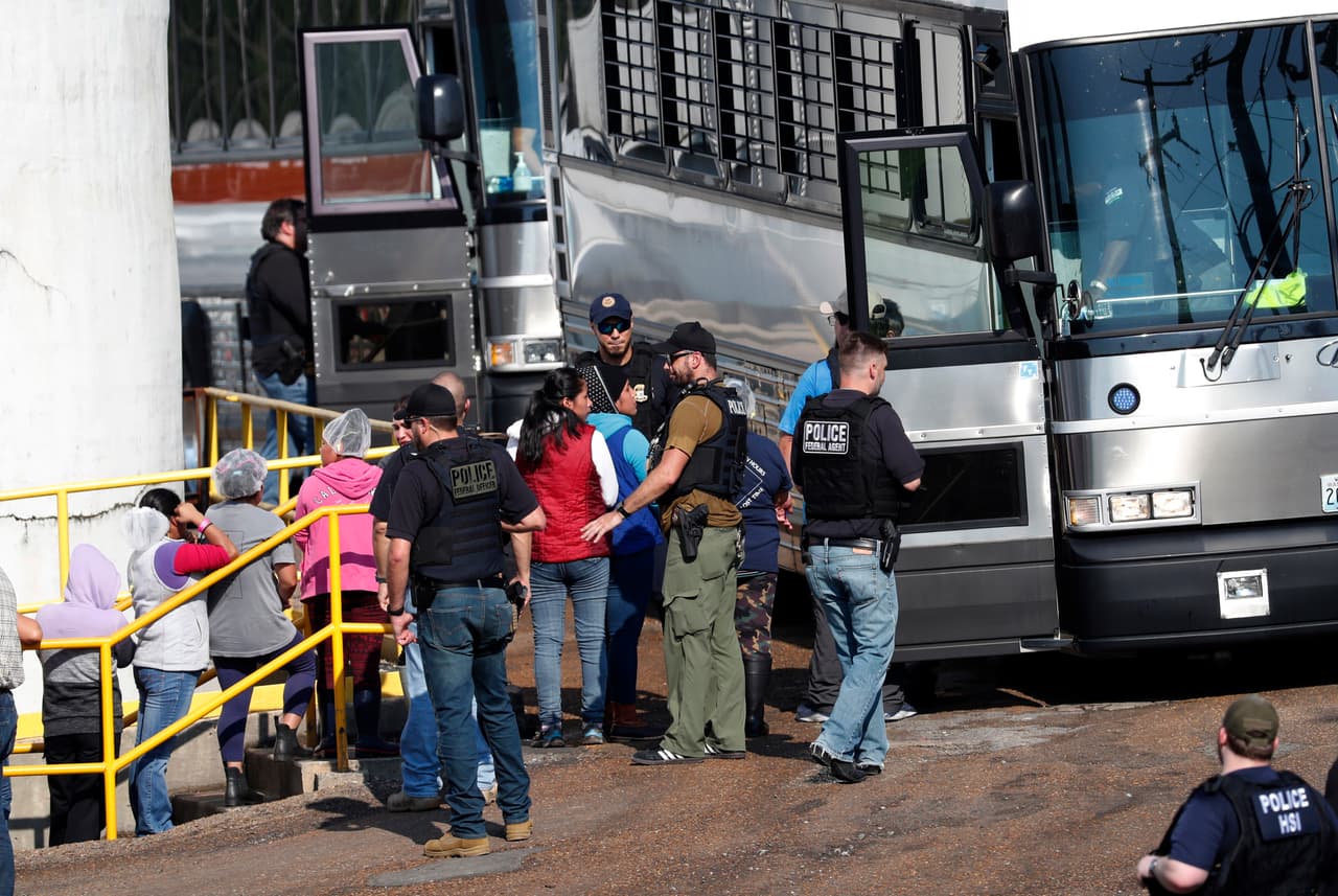 Un grupo de mujeres arrestadas es escoltado hasta uno de los autobuses que custodian las autoridades migratorias para llevarlas a un centro de detención.