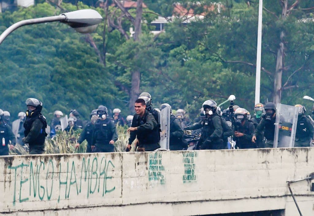 En otra imagen de la misma serie de la agencia France-Presse, ahora sin máscara, un funcionario del Estado con un arma de fuego en la mano.
