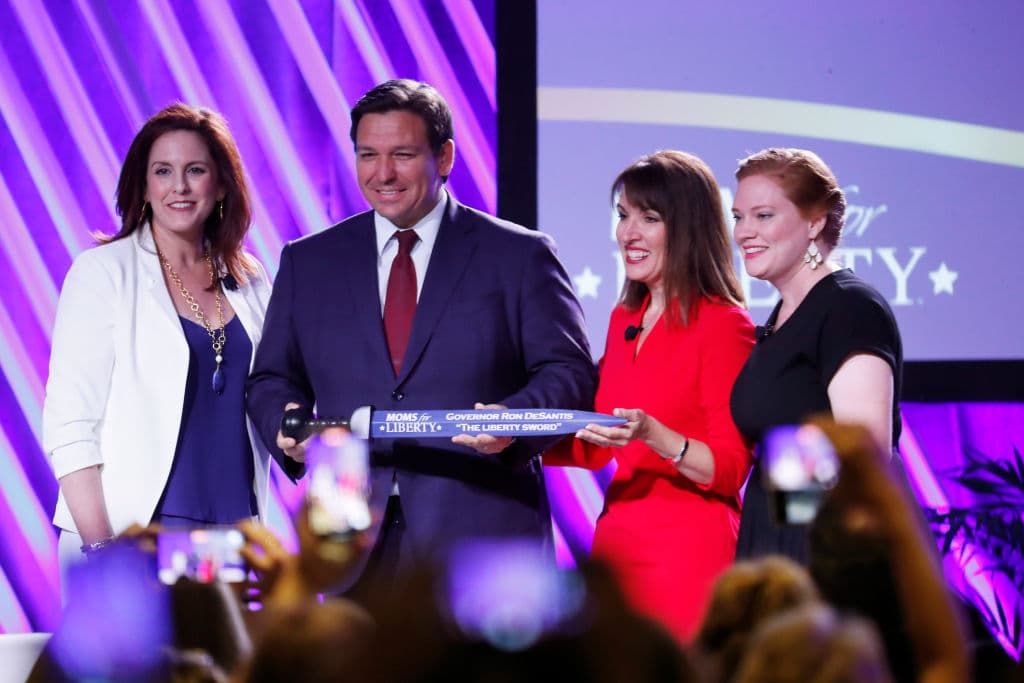 Las líderes de 
<i>Moms for Liberty</i>, Tiffany Justice, Tina Descovich y Marie Rogerson presentan la 'Espada de la Libertad' al gobernador de Florida, Ron DeSantis, antes de su intervención en la primera cumbre de la organización, el 15 de julio de 2022 en Tampa.