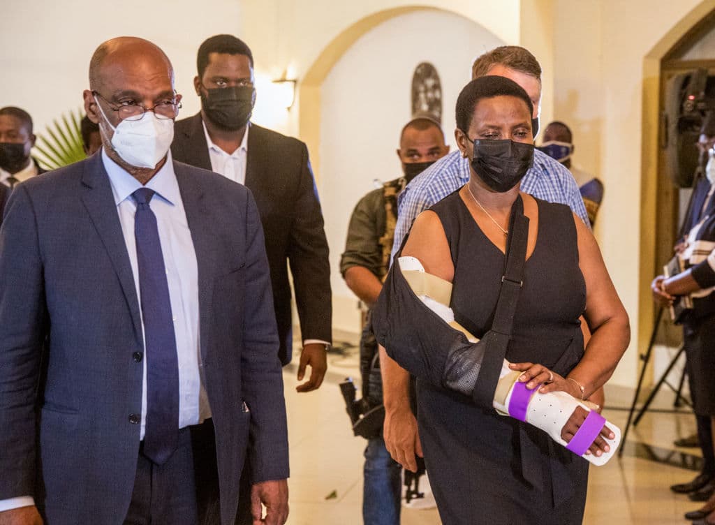 El primer ministro Ariel Henry (izq.) camina con la primera dama Martine Moise al salir de la ceremonia católica de velatorio del presidente Jovenel Moïse en el Hotel Roi Christophe, en Cap-Haitien, el 22 de julio de 2021.