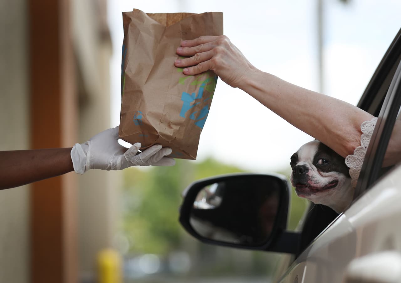 <b>Entrega de comida con precaución.</b> Un empleado de Taco Bell entrega un pedido a un cliente en la ventanilla de un restaurante el 31 de marzo, en Hollywood, Florida. Ron DeSantis, gobernador de ese estado, declaró 30 días de aislamiento a los habitantes el 1 de abril.