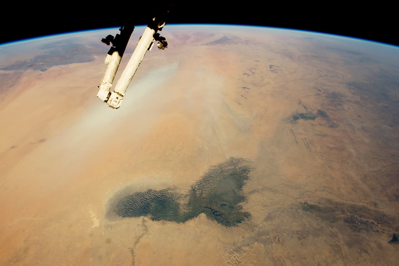 Esta imagen muestra paisajes del árido desierto del Sahara y la vegetación más oscura del bosque húmedo tropical semiárido conocido como Sahel. Las marismas verde oscuro del lago Chad se destacan en el primer plano de esta vista.