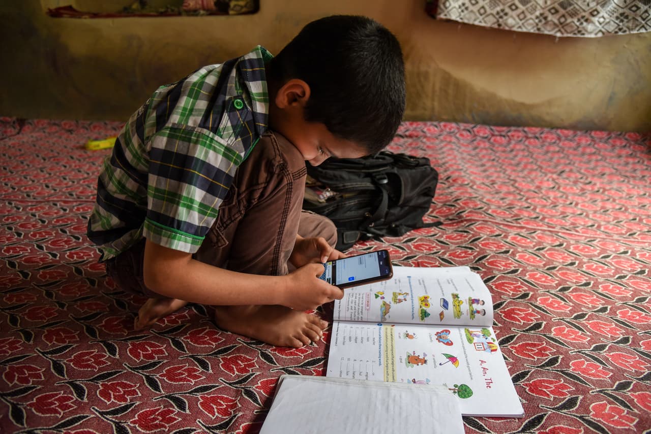 <b>Un teléfono móvil y un libro</b>. Un estudiante de Cachemira escucha a su maestro durante una clase en línea a través de la aplicación Zoom el 1 de mayo. Los estudiantes en esta región han sufrido los bloqueos de la señal de internet, 
<a href="https://www.univision.com/noticias/premio-pulitzer-2020-imagenes-de-represion-y-violencia-se-llevan-el-maximo-galardon-del-periodismo-estadounidense-fotos">una consecuencia del conflicto político y militar en la región</a>.