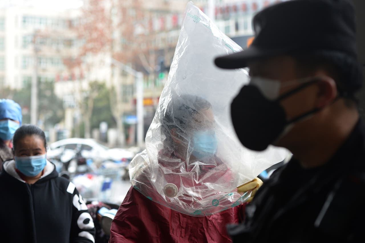 Un residente de Wuhan se protege con una máscara y una bolsa de plástico sobre el rostro frente a un supermercado, el 10 de febrero de 2020. La importante cadena de alimentos Jiumaojiu International Holdings dijo el domingo por la noche que extenderá la suspensión de todos sus actividades en locales autogestionados y franquicias en China, que han estado cerrados desde el 29 de enero.