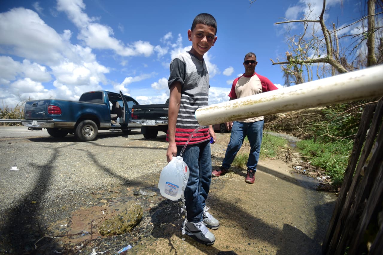 Dereck Laguna, de 13 años, acompaña a su padrastro José Figueroa mientras se detienen en la carretera donde encontraron agua en Cayey, Puerto Rico.