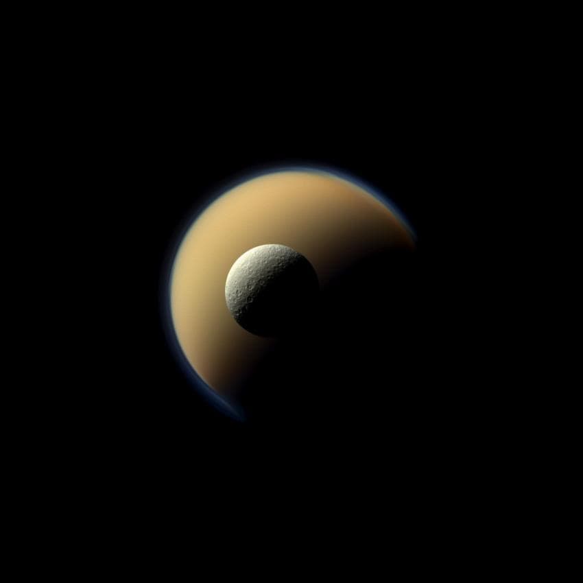 Historia de dos lunas. El cuerpo más brillante en el sistema solar, Encelado, se contrasta aquí contra la oscuridad dorada y húmeda de Titán.