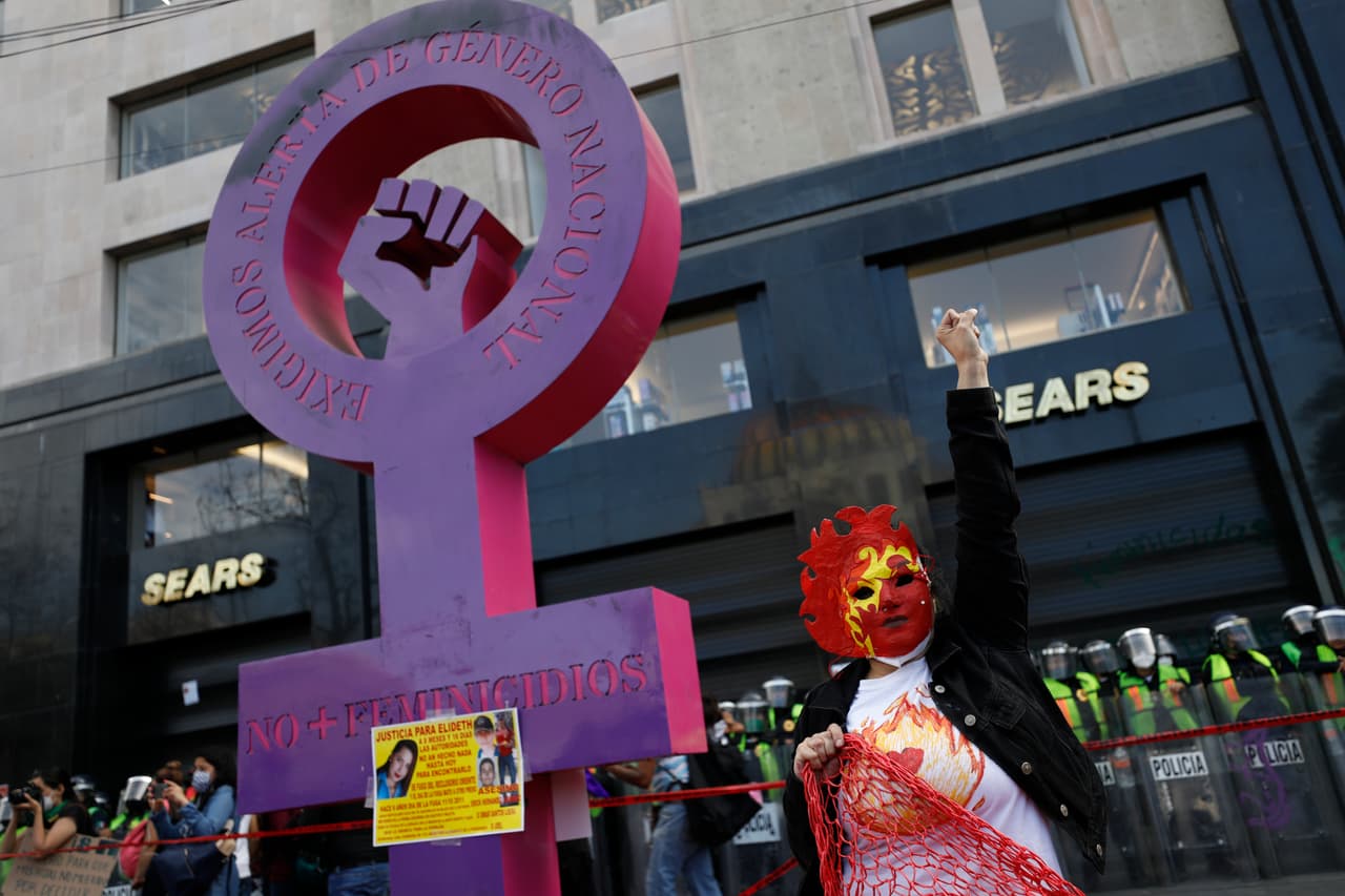 Una mujer enmascarada levanta el puño al lado de la estructura denominada 'Antomonumenta', que fue puesta en honor a las miles de víctimas de feminicidios en el país.