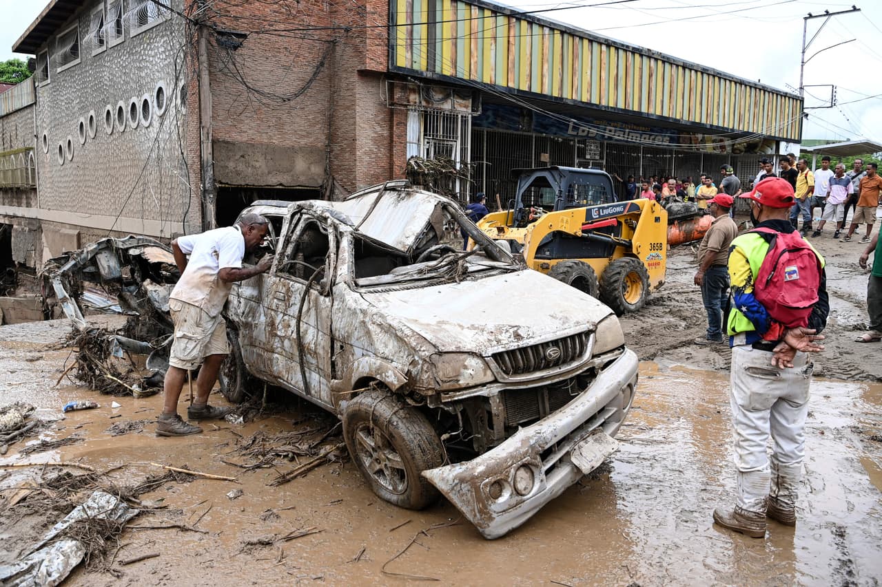 Un hombre mira dentro de un vehículo destruido arrastrado por un deslizamiento de tierra durante las fuertes lluvias en Las Tejerias, estado de Aragua, Venezuela, el 9 de octubre de 2022.