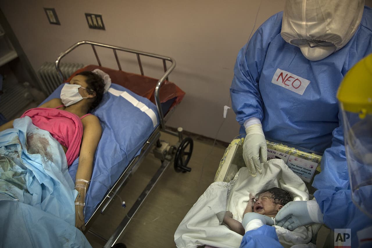 Un neonatólogo examina a la bebé recién nacida de María Álvarez en el Instituto Nacional Materno Perinatal, 
<b>mientras ella descansa a un costado en una cama. </b>
<br>