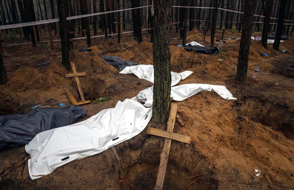 El Ministerio de Defensa de Ucrania publicó fotos de tumbas marcadas con cruces de madera y una gran zanja rodeada por investigadores. Señaló que algunas de las tumbas estaban “frescas”.