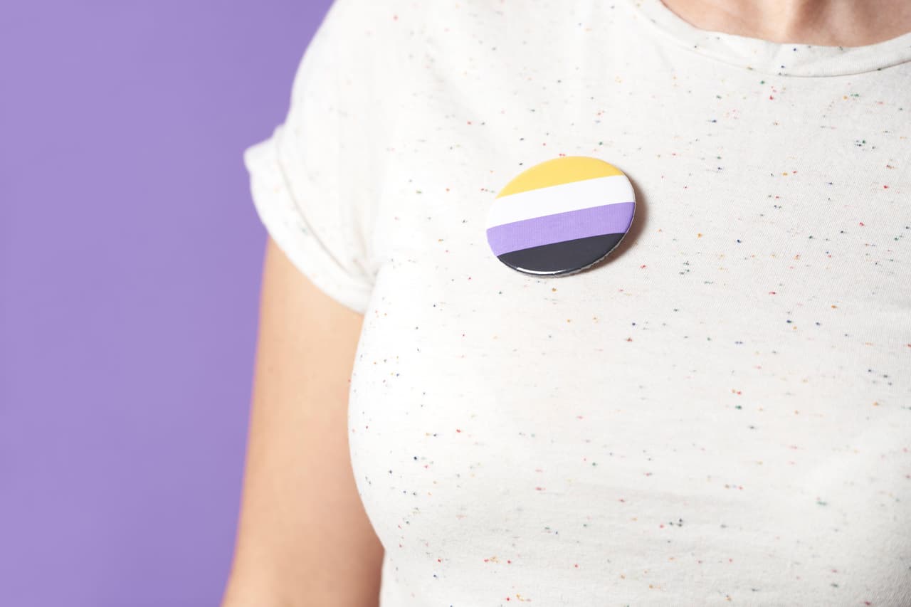 Persona con pin de la bandera no binaria
