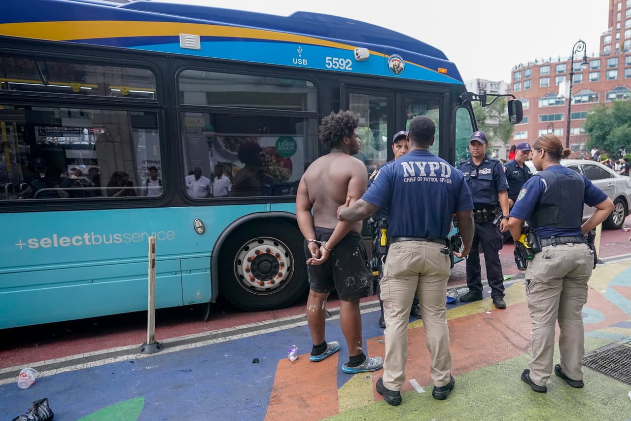 La Policía se lleva esposado a un sospechoso de haber participado en actos de vandalismo.