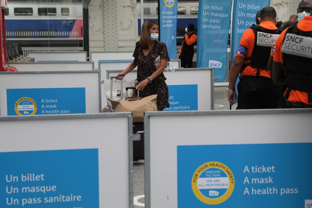 Una mujer pasa junto a carteles que leen "Un billete, una mascarilla, un pase de salud" en la estación de tren Gare de Lyon en París. Desde el pasado lunes, el pase de vacunación será necesario en Francia para acceder a cafés, restaurantes, -viajes a distancia y, en algunos casos, hospitales. Ya estaba en funcionamiento para espacios culturales y recreativos, incluidos cines, salas de conciertos, estadios deportivos y parques temáticos con capacidad para más de 50 personas.