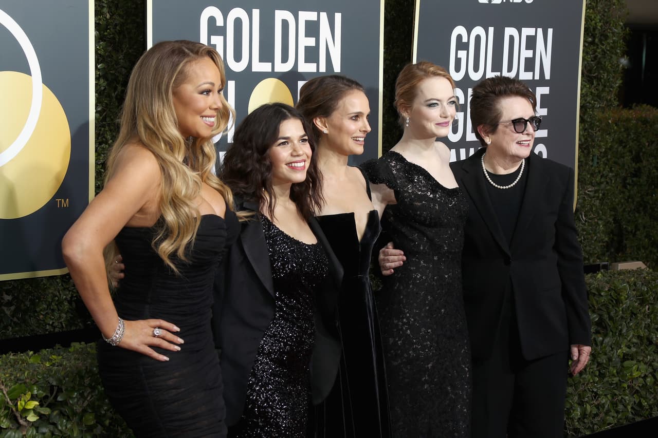 El color negro de los vestidos fue dominante sobre la alfombra roja para contribuir a generar conciencia sobre el movimiento 'Time's Up' y centrar la conversación en la protesta por los acosos, en vez de en las habituales conversaciones superficiales sobre el aspecto físico de las actrices. En esta fotografía se ve a la cantante Mariah Carey, a las actrices América Ferrera, Natalie Portman y Emma Stone, y a la derecha posa la célebre exprofesional del tenis Billie Jean King, quien fue la principal promotora de la lucha por la igualdad entre hombre y mujer en ese deporte en la década de 1970 en EEUU.