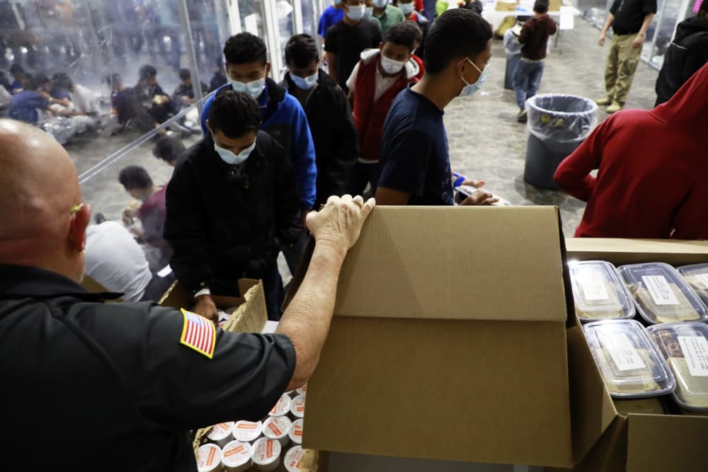 Un funcionario de la Patrulla Fronteriza reparte comida a los migrantes en el centro de Donna.