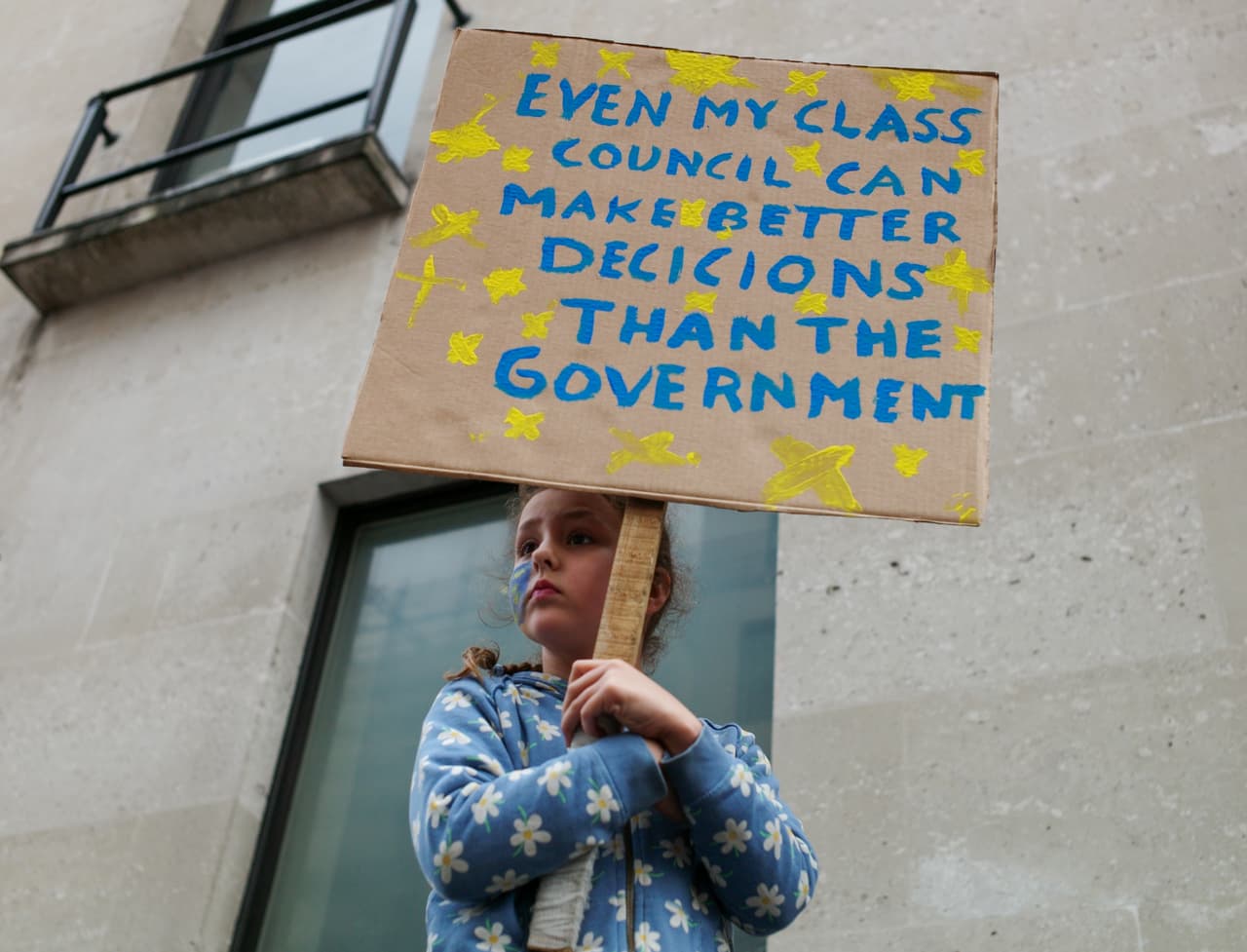 Una niña que participó de la protesta sostiene una pancarta en la que se lee "incluso mi consejo estudiantil puede tomar mejores decisiones que el gobierno".