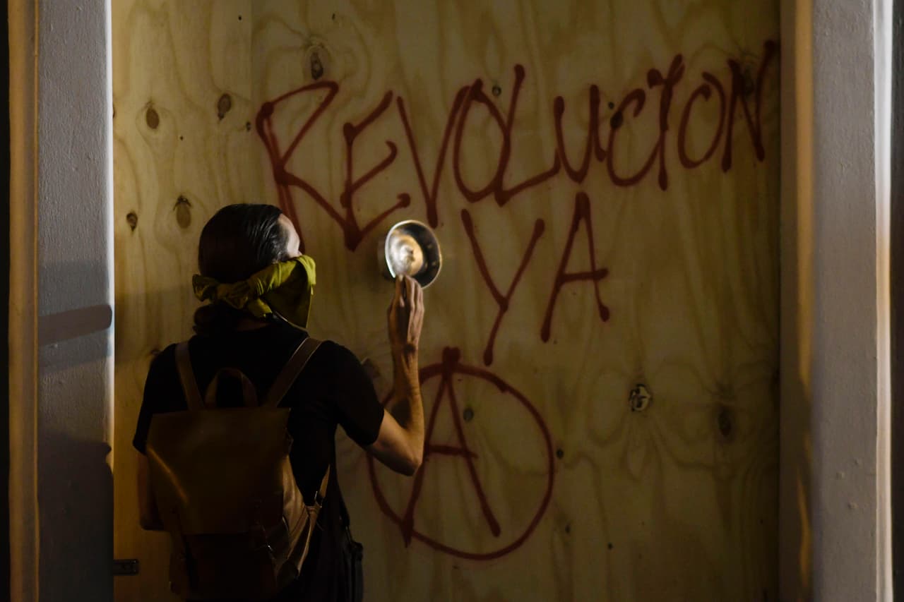Un manifestante le da a un panel de madera con una cacerola. 
<br>