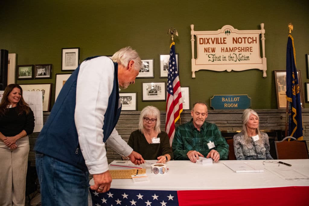 Un residente de Dixville Notch muestra su identificación al registrarse para emitir su voto en las elecciones de EEUU 2024 a la medianoche en el Balsams Grand Resort. La vicepresidenta Kamala Harris y el expresidente Donald Trump han empatado con tres votos cada uno.