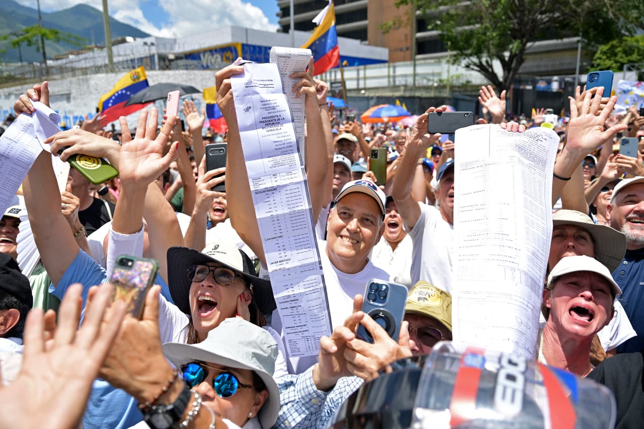 La gente grita consignas y muestra sus actas de votación durante la protesta convocada por la oposición para que se reconozca la "victoria" electoral, en Caracas el 17 de agosto de 2024.