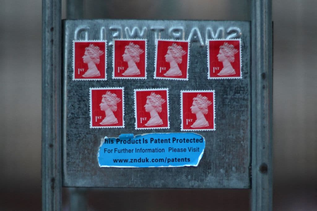 Esta imagen de un sello de primera clase con la imagen de la reina Isabel II apareció este viernes pegada a las rejas que rodean el Palacio de Buckingham en Londres.