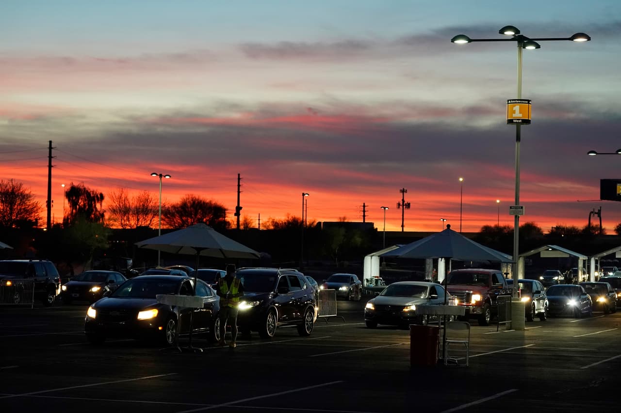 Los vehículos se alinean para que las personas puedan obtener sus tarjetas de vacunación covid-19 después de haber sido vacunadas en un drive-thru en el estacionamiento del State Farm Stadium, en Glendale, Arizona.