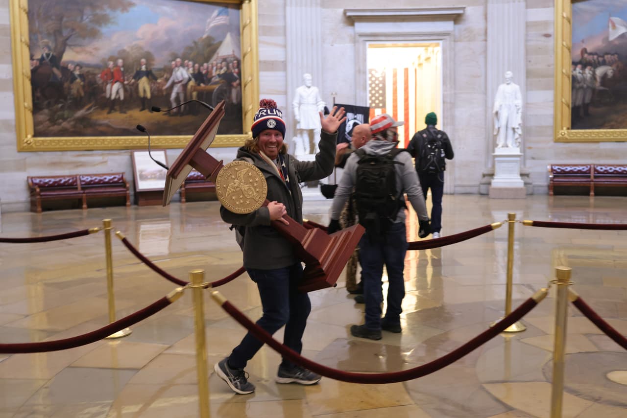 <b>Un paseo con el atril de la presidenta Pelosi</b>
<br>
<br>Adam Johnson, un partidario de Trump oriundo de Florida, fue fotografiado caminando sonriente con el atril de la presidenta de la Cámara de Representantes, Nancy Pelosi.
<br>
<br>Johnson 
<a href="https://www.washingtonpost.com/dc-md-va/2021/11/22/pelosi-lectern-defendant-guilty-plea/"><u>se declaró culpable</u></a> de ingresar y permanecer en un edificio restringido y a cambio los fiscales acordaron desestimar los cargos de robo de propiedad del gobierno.
<br>
<br>
<a href="https://www.univision.com/noticias/politica/carcel-arrestos-domiciliarios-libertad-condicional-multas-asaltantes-capitolio-fotos"><u>Vea aquí el panorama legal de los implicados en el asalto al Capitolio</u></a>