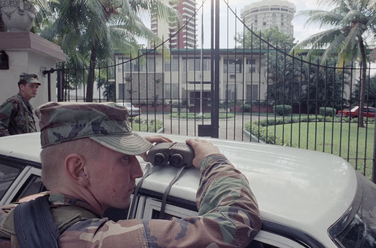 El teniente Daniel Barnett, de Ohio, maneja los prismáticos frente a la puerta principal de la Embajada del Vaticano, el sábado 7 de enero de 1989 en la ciudad de Panamá, donde tres días antes el hombre fuerte Manuel Noriega se entregó a las autoridades estadounidenses.