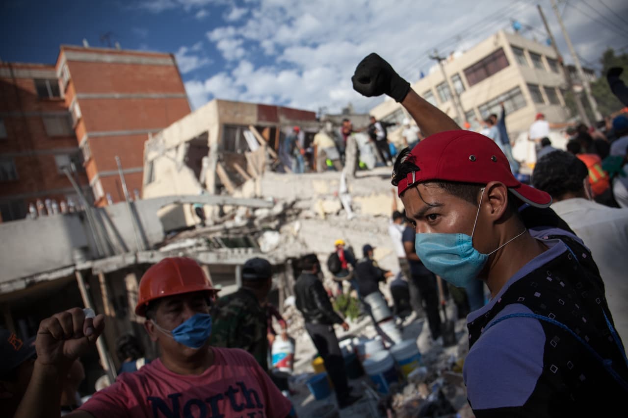 Rescatistas y voluntarios propagan con sus puños en alto la orden de mantener el silencio alrededor de los edificios en ruinas. Al menos dos escuelas fueron derrumbadas por el sismo de magnitud 7.1.