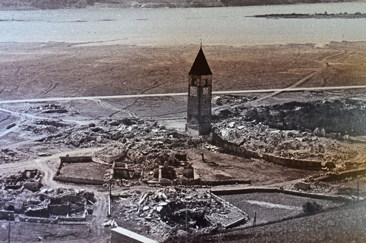 Algunos creían que las casas intactas estaban sumergidas, pero habían sido demolidas antes de la inundación, como asegura una
<a href="https://www.travelreportage.com/2016/10/24/all-about-reschensee-a-k-a-lake-reschen/"><u> recomendación de viajes</u></a> de travelreportaje.com. La foto, también del museo de Curon Venosta, muestra los alrededores de la iglesia demolidos antes de la fusión de los lagos.