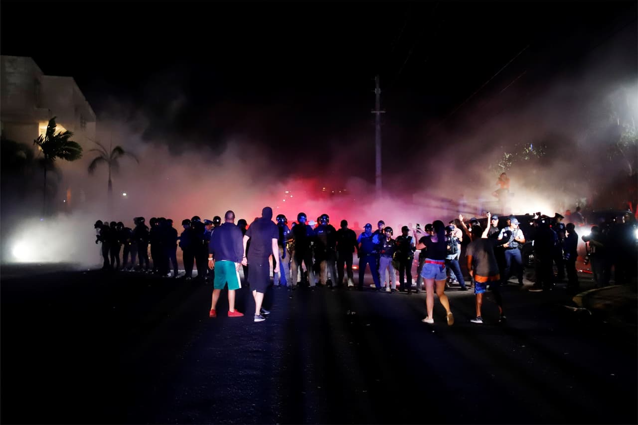La 
<b><a href="https://www.univision.com/noticias/politica/ricardo-rosello-renuncia-a-la-presidencia-de-su-partido-y-a-la-reeleccion-pero-se-niega-a-dimitir" target="_blank">decisión de Ricardo Roselló de renunciar a la reeleción</a></b> y a la presidencia de su partido, pero no al cargo, no satisfizo a los puertorriqueños que volvieron a salir el domingo en la tarde-noche a exigir su dimisión. Y como en otras ocasiones, hubo algunos enfrentamientos con las fuerzas de seguridad. En la imagen, un grupo de manifestantes se enfrentó a la policía mientras Ricardo Rosselló se reunía con alcaldes federados tras su mensaje, fuera del Centro Cultural Yolanda Guerrero, en Guaynabo.