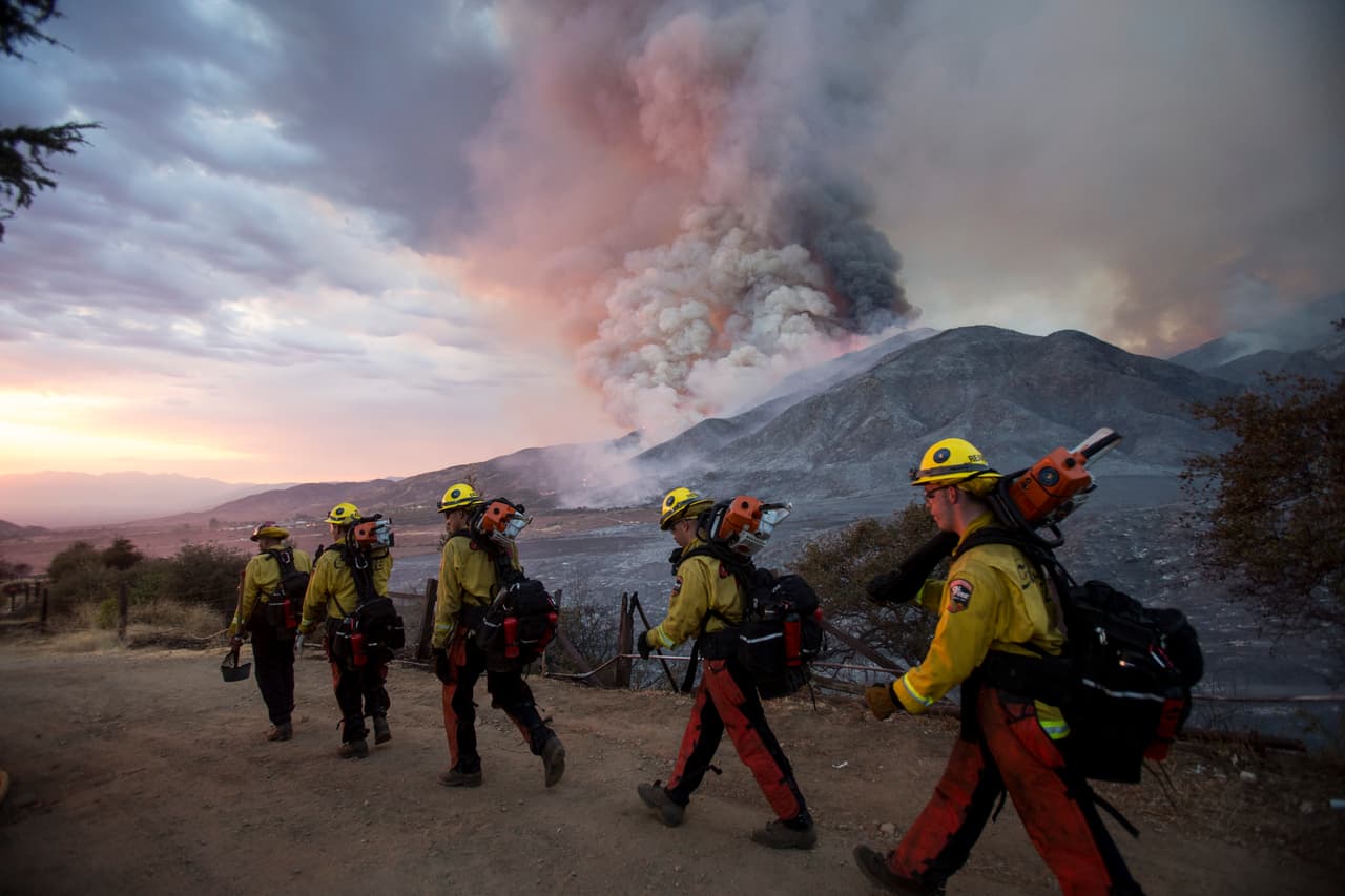 Miembros de los bomberos caminan en fila durante un incendio forestal en Yucaipa, California. Tres incendios forestales de 
<a href="https://www.univision.com/temas/california">California</a> que se propagaron rápidamente hicieron huir a los habitantes. Una brutal ola de calor 
<b>empujó las temperaturas a tres dígitos en muchas partes del estado.</b>
