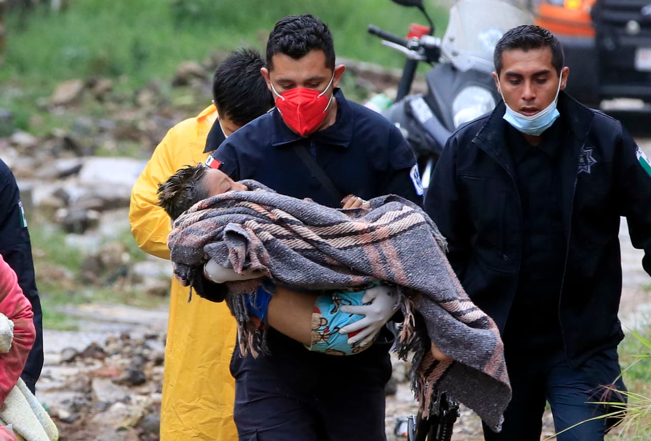 Un socorrista carga a un menor luego de que un deslave destruyera una casa en el barrio de Loma Bonita, en Xalapa.