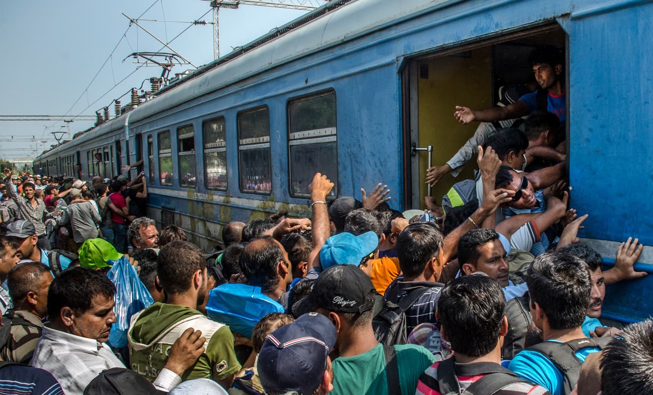 <b>Capítulo 3. “Somos personas, no somos animales”. </b>Un policía se lleva detenidos a los dos periodistas. No tienen el permiso escrito, diario, para hacer fotografías en la caótica estación. Tras casi una hora detenidos son puestos en libertad con la amenaza de peores consecuencias. Dos veces más serán detenidos en los siguientes días, afortunadamente sin graves problemas. Pasan las horas y el viejísimo tren de metal se convierte en un horno para las personas hacinadas en su interior. Las escasas botellas de agua se convierten en una necesidad absoluta para los niños, que casi no pueden ni respirar dentro de los vagones. Por las ventanillas abiertas se ven bebés asomados, sujetos por sus agobiados y sudorosos padres, cuyos ojos se iluminan cuando alguien les entrega un poco de agua desde el andén. Las escenas de la estación recuerdan a los vagones de ganado en el que los judíos eran llevados a los campos de exterminio. 
<b><a href="http://huelladigital.univisionnoticias.com/crisis-refugiados-javier-bauluz/capitulo-3/">(VER ESPECIAL COMPLETO).</a></b>