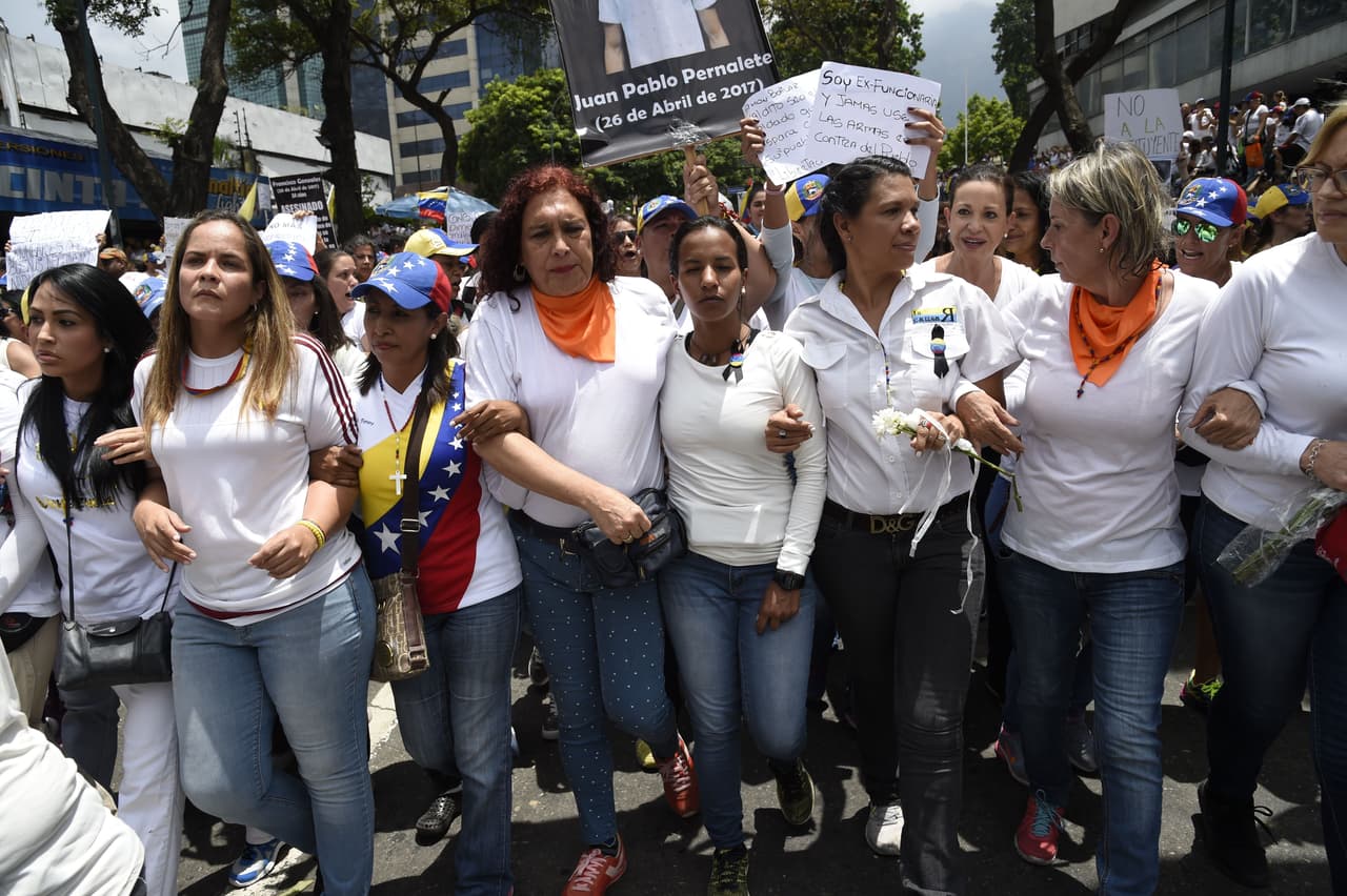 Encabezadas por diputadas como 
<a href="http://especiales.univision.com/perfiles-nueva-venezuela/tamara-adrian/">Tamara Adrián</a> y 
<a href="http://especiales.univision.com/perfiles-nueva-venezuela/marialbert-barrios/">Marialbert Barrios</a>, miles de mujeres caminaron rumbo al Ministerio de Interior y Justicia, en el centro de Caracas, para rechazar que los cuerpos de seguridad dispersen las protestas contra el gobierno con gases lacrimógenos, perdigones y chorros de agua a presión. Al fondo, el nombre de uno de los jóvenes fallecidos: Juan Pablo Pernalete.
