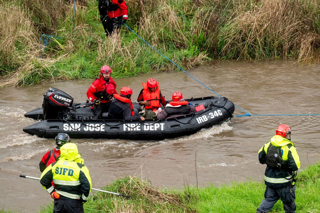 Trabajadores de búsqueda y rescate evacuan a hombres de un campamento para personas sin hogar que quedó rodeado por las inundaciones del río Guadalupe el domingo 4 de febrero de 2024 en San José, California. El segundo de los ríos atmosféricos consecutivos está empapando el norte de California, inundando carreteras, dejando sin electricidad a decenas de miles de personas y llevando a los meteorólogos a advertir sobre posibles vientos huracanados y deslizamientos de tierra a medida que avanza hacia el sur en los próximos días. (Foto AP/Noah Berger)