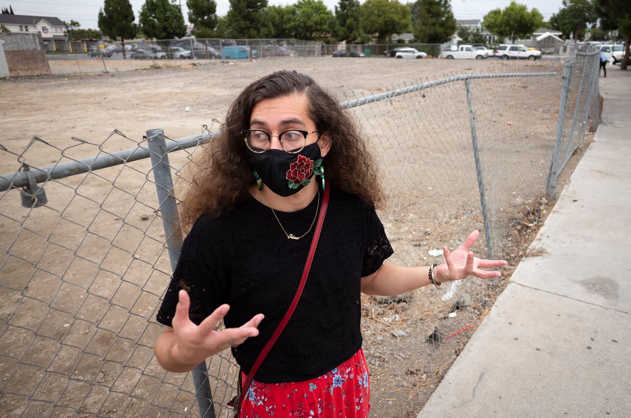 Patricia J. Flores Yrarrázaval, directora de proyectos de Orange County Environmental Justice, discute planes para atender la contaminación debido al plomo en el lote de tierra a su espalda, que pertenece a Santa Ana.