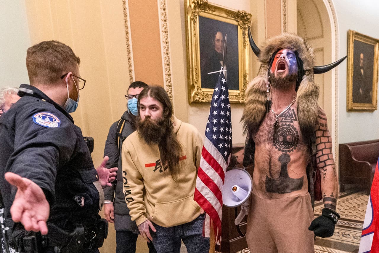 <b>Un grito solicitando permiso para buscar a los congresistas</b>
<br>
<br>En diversas fases del incidente la policía pudo detener o desviar a la turba dentro del Capitolio. Esta foto muestra a un grupo que fue detenido por un grupo de policías en su camino dentro del Congreso. 
<br>
<br>Durante unos minutos los asaltantes explicaron a las autoridades las razones de su entrada violenta y solicitaron que se les permitiera continuar.
<br>