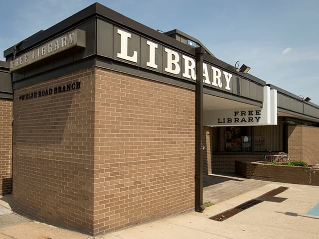 <b>Welsh Road Library</b>
<br>9233 Roosevelt Boulevard
<br>Philadelphia, PA 19114-2205
<br>215-685-0498
<br>
<br>Welsh Road lleva el nombre de los colonos galeses del norte de Gales que bajaron por este camino accidentado en el siglo XVIII para ir al molino de Pennypack Creek. La sucursal de 
<a href="https://libwww.freelibrary.org/locations/welsh-road-library" target="_blank">Welsh Road</a> se abrió al público el 11 de noviembre de 1968. La biblioteca fue una de las primeras del país que se construyó en un centro comercial, aunque en realidad se encuentra en la parte trasera del Centro Comercial Northeast. La biblioteca tiene un diseño futurista que se basa en tres paredes de vidrio para agregar a la iluminación interior.
<br>