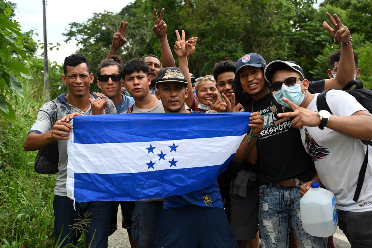 Migrantes hondureños, parte de una caravana que se dirige a Estados Unidos, posan con una bandera de Honduras cerca de Izabal, Guatemala, el 2 de octubre de 2020.