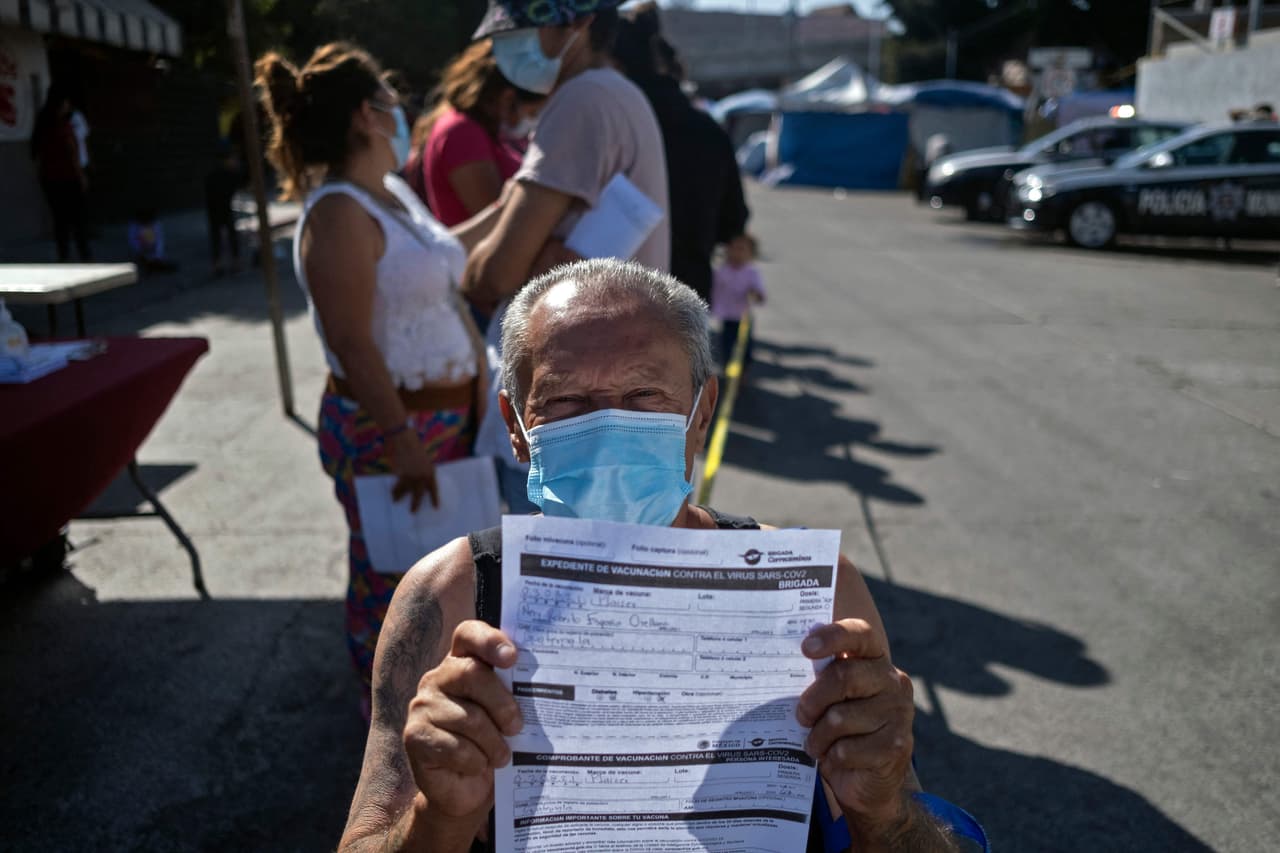 El inmigrante guatemalteco Nery Roberto Espana, que acampa en El Chaparral, muestra el registro de vacunación después de recibir una primera dosis en Tijuana.