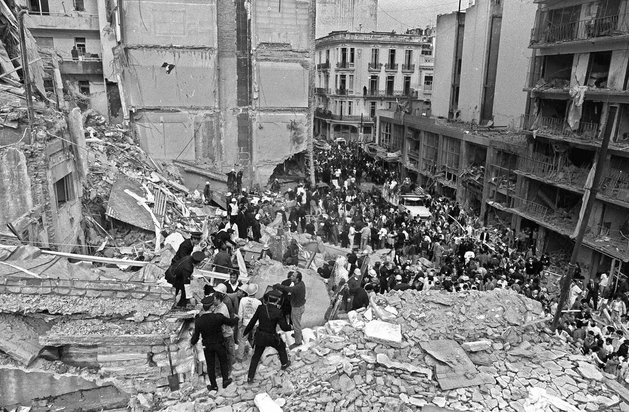 Las investigaciones de este atentado, el peor en suelo argentino, ha tenido pocas certezas sobre los autores materiales e intelectuales del crimen y solo han sido juzgados algunos funcionarios acusados de encubrimiento. En la fotografía, agentes de policía y bomberos buscan sobrevivientes bajo los escombros.