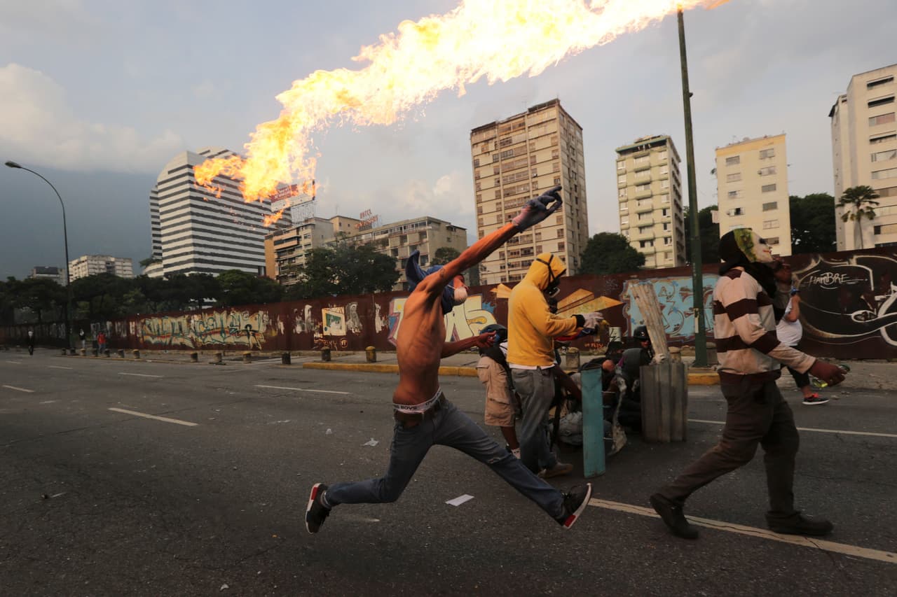 Un manifestante opositor lanza un ‘coctel molotov’ a la policía.
<br>