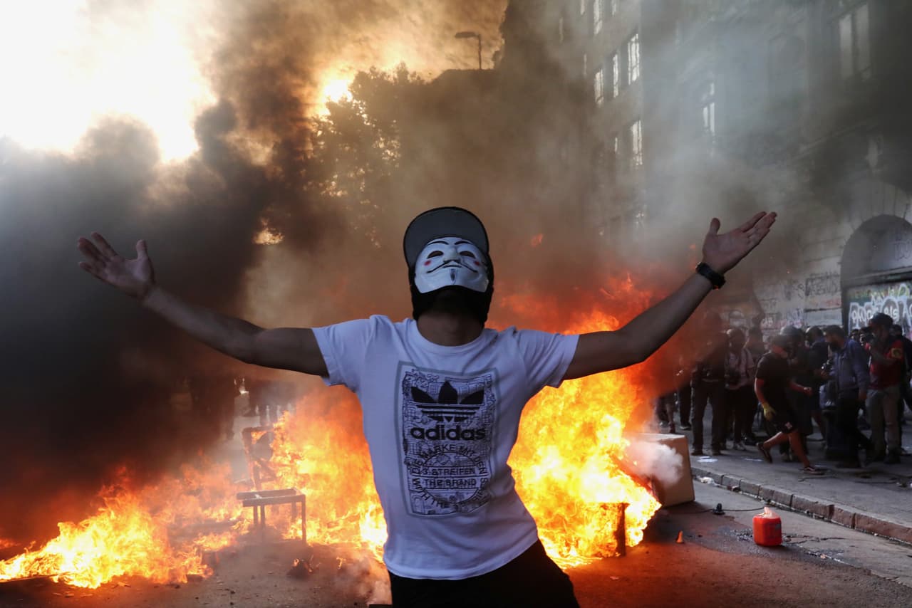Un joven manifestante gesticula frente a una barricada ardiendo durante una de las protestas el 28 de noviembre del 2019. Para apaciguarlas, el presidente Piñera 
<b>anunció una batería de medidas, como mejorar el acceso a la salud</b> en el país que sufre de una profundad desigualdad social a pesar del sostenido crecimiento económico.