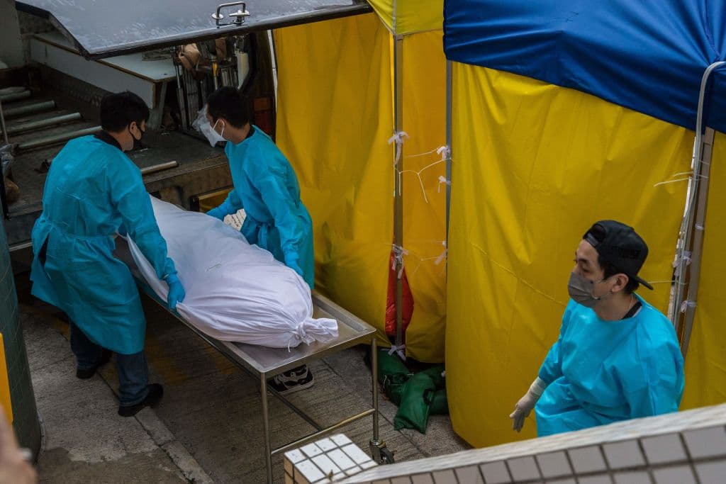 La imagen de un cuerpo siendo movido a un vehículo. Hong Kong atraviesa su peor ola de contagios en momentos en que el resto del mundo levanta las medidas de contingencia para la propagación del virus y se prepara para la siguiente fase, la de convivir con él.