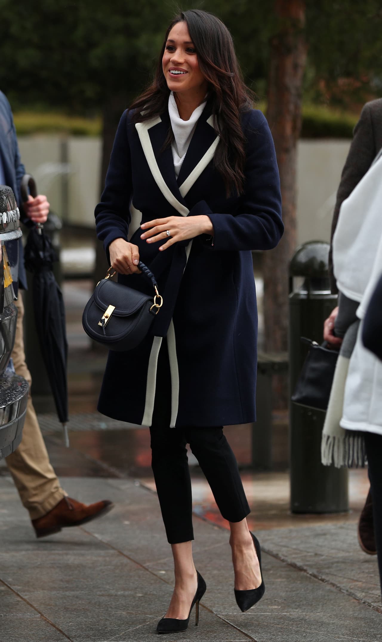 <b>8 de marzo, 2018</b>
<br>En su visita a Birmingham, la actriz eligió un abrigo la marca J Crew con vivos blancos ligeramente oversize y zapatos Manolo Blahnik. En la mano repitió uno de sus pequeños bolsos con mango en azul marino de Altuzarra.