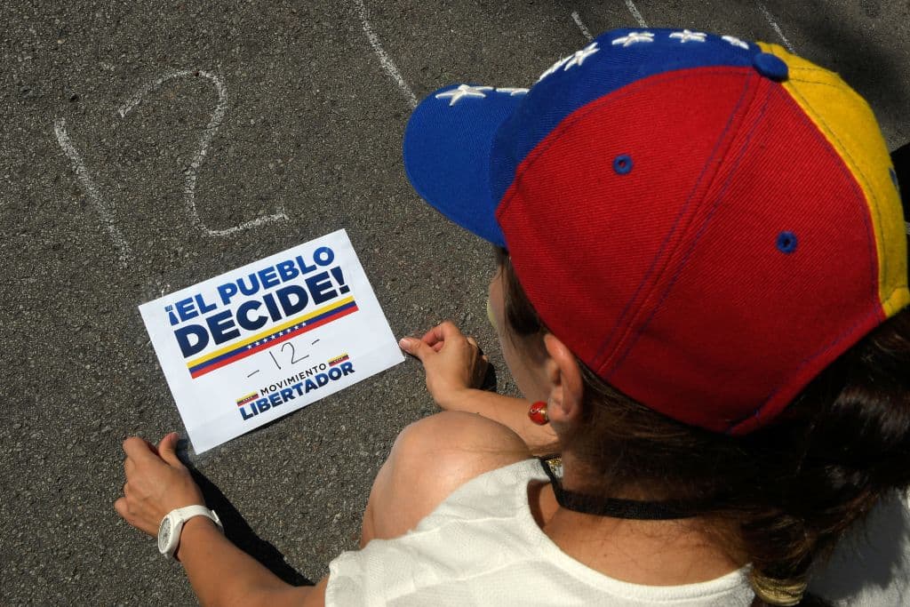 Una voluntaria prepara indicaciones para ordenar las filas de asistentes en Barcelona al plebiscito simbólico para decidir sobre la Asamblea Constituyente convocada sin consulta por el presidente Nicolás Maduro.