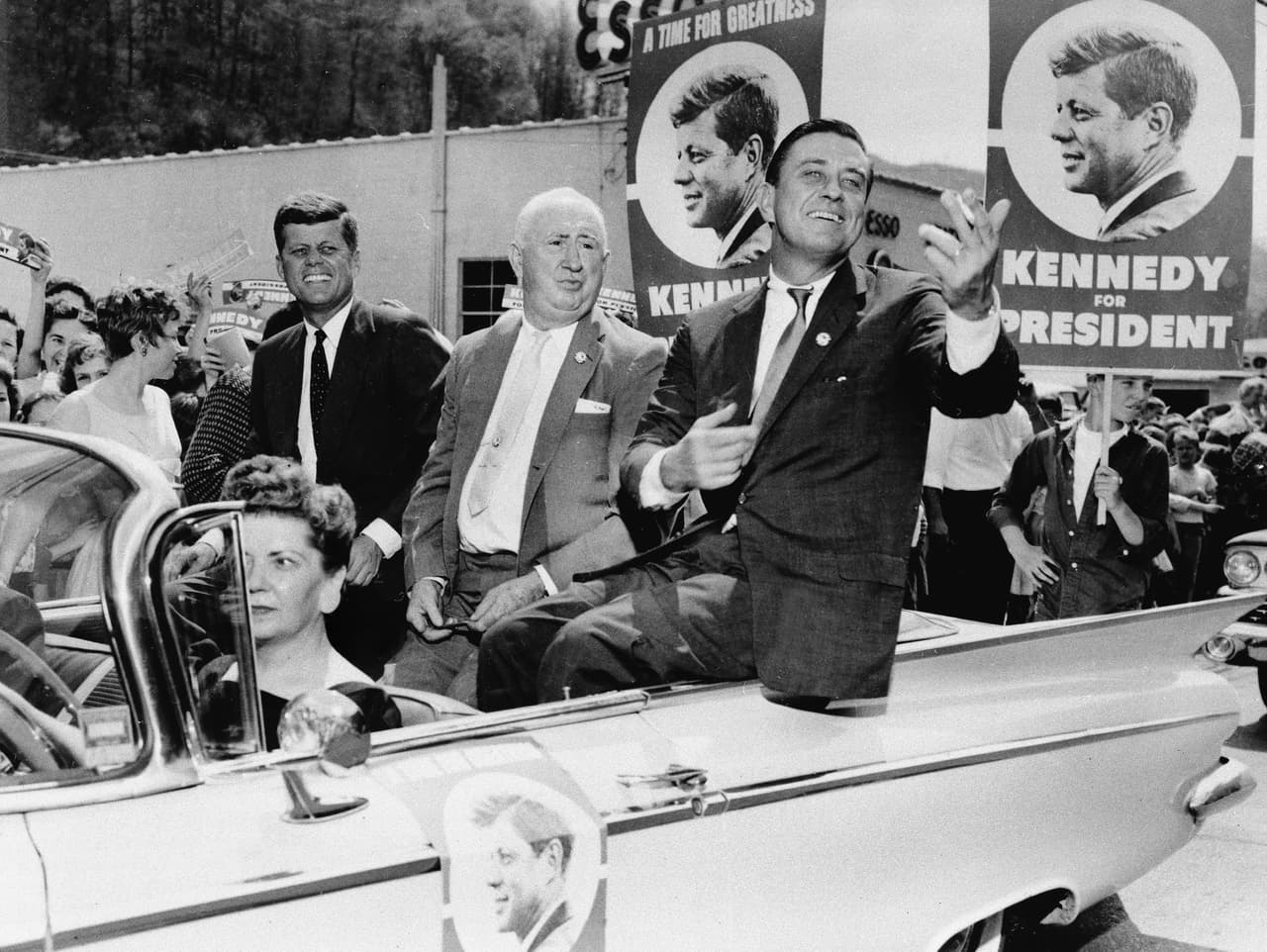 A principios de 1960, JFK hizo pública su intención de competir por la nominación demócrata a la presidencia. Seleccionó a su contrincante Lyndon Johnson como compañero de fórmula, quien se juramentaría como Presidente en el avión presidencial luego del asesinato de JFK. La contienda presidencial contra el republicano Richard Nixon fue la primera con debates presidenciales televisados, ahora rutinarios en la política de EEUU. La fotografía muestra a JFK en campaña, junto a otros compañeros demócratas en Virginia Occidental, el 27 de abril de 1960.