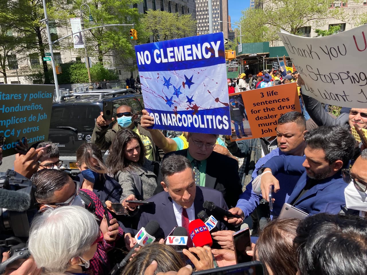 El abogado defensor Raymond Colon habla con los medios de comunicación a las puertas del tribunal de Manhattan donde su cliente, el ex presidente hondureño Juan Orlando Hernández, será juzgado el 17 de enero de 2023. El letrero detrás de él dice: "No hay clemencia para la narcopolítica".