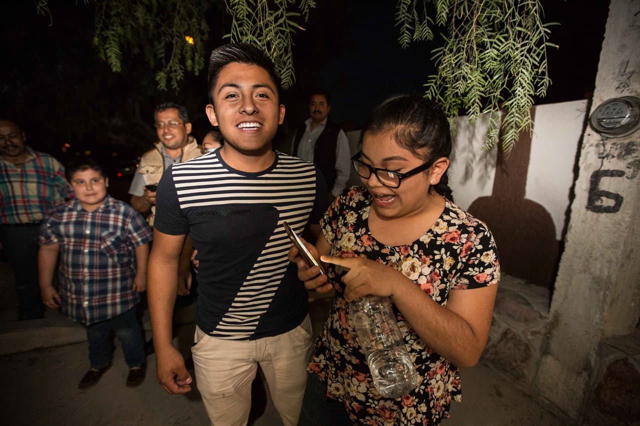 Daniel Muñoz, 17, y Valeria Muñoz, 16, fuera de la casa de Rubí Ibarra la noche antes de los festejos. Valeria, quien no celebró sus 15, reacciona al ver la foto que han conseguido tomarse con Rubí después de explicarle a la familia a través del muro que rodea su casa que han hecho un viaje largo desde lejos y solo quieren saludarla. Después de tomarse la foto se marcharon de regreso a casa sin quedarse a la fiesta. Almudena Toral