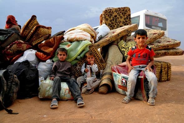 Estos niños descansan sentados sobre sus pertenencias luego de un largo trayecto para llegar a la frontera con Turquía.